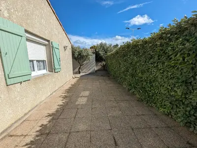 a sidewalk next to a building with a green hedge at Villa T3 Spacieuse à Port-la-Nouvelle – Jardin, Parking, à 900m de la Plage, Chien Admis - FR-1-797-50 in Port-la-Nouvelle
