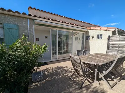 a wooden table and chairs on a patio at Villa T3 Spacieuse à Port-la-Nouvelle – Jardin, Parking, à 900m de la Plage, Chien Admis - FR-1-797-50 in Port-la-Nouvelle