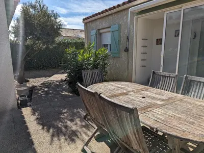 a wooden table and chairs in front of a house at Villa T3 Spacieuse à Port-la-Nouvelle – Jardin, Parking, à 900m de la Plage, Chien Admis - FR-1-797-50 in Port-la-Nouvelle