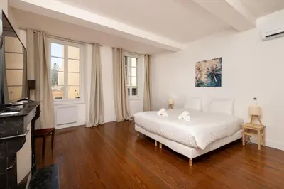 a white bedroom with a bed and a television at Le Grand Authentique in Carcassonne