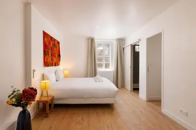 a white bedroom with a bed and a vase of flowers at Le Grand Authentique in Carcassonne