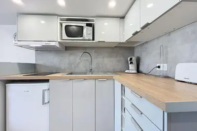 a kitchen with white cabinets and a microwave at Studio with pool near the harbor in Gruissan