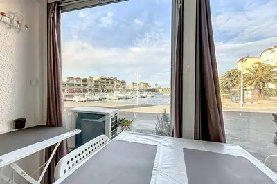 a room with a table and a window with a view at Studio with pool near the harbor in Gruissan