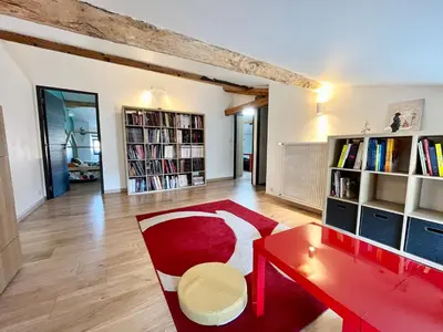 a living room with a red table and bookshelves at La circulade - Maison de caractère avec jardin in Bram