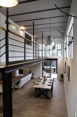 a large living room with a table and a staircase at L'atelier de 1900 in Puicheric