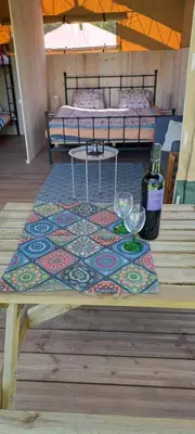 a table with wine glasses and a bed in a room at Lodge Safari tent in Camurac