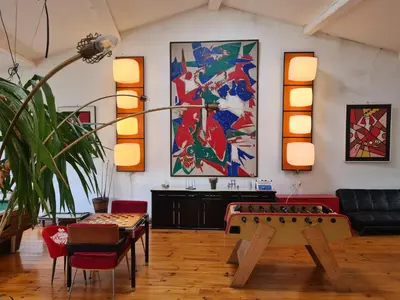 a room with a table and chairs and paintings on the wall at Loft au piémont des Pyrénées Cathares in Sainte-Colombe-sur-lʼHers