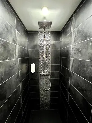 a bathroom with a shower with black tiles at SUNNY , terrasse, climatisation, centre ville in Carcassonne