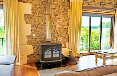 a living room with a fireplace and a stone wall at La Bastide in Puycalvel Lautrec