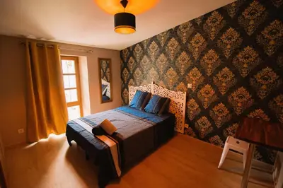 a bedroom with a bed with a blue comforter and a window at Tout confort ! Ville, Calme, Cinéma privé, Climatisation, Parking, WiFi in Carcassonne