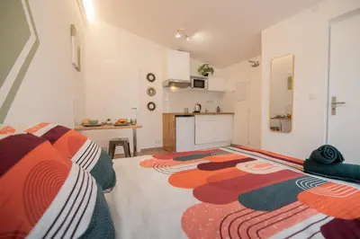 a bedroom with a bed with a colorful blanket on it at Tout confort ! Ville, Climatisation, Parking, Wifi, Calme, TV in Carcassonne