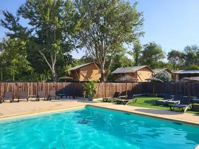 a swimming pool with chairs and a fence at Camping Le Val de Cesse in Mirepeisset