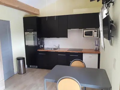a kitchen with black cabinets and a table with chairs at Maison Des Levriers met zwemvijver en airco in Katharenland in Luc-sur-Aude