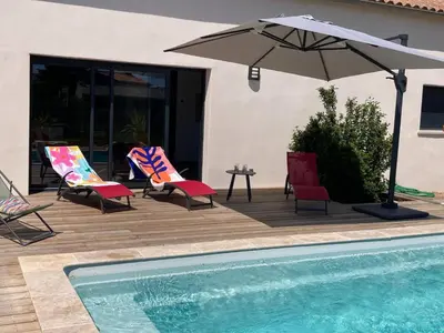 a patio with chairs and an umbrella next to a pool at Stylish Villa in Sainte-Valière in Sainte-Vallière