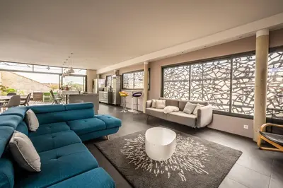 a large living room with a blue couch and chairs at Le Couvent des Ursulines - Penthouse climatisé piscine in Narbonne