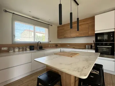 a kitchen with a marble counter top and a island at Maison paisible toute équipée, piscine chauffée in Sallèles-dʼAude