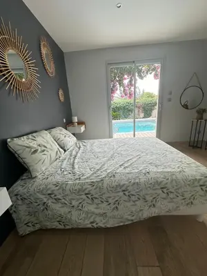 a bedroom with a bed and a mirror on the wall at Maison paisible toute équipée, piscine chauffée in Sallèles-dʼAude