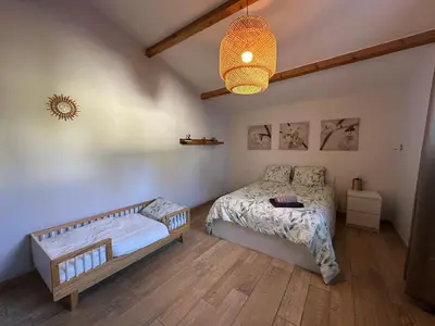 a bedroom with a bed and a chandelier at Maison paisible toute équipée, piscine chauffée in Sallèles-dʼAude