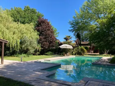 a swimming pool in a yard with an umbrella at Maison exceptionnelle piscine in Aussillon