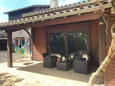 a building with a patio with chairs and a hammock at Maison exceptionnelle piscine in Aussillon