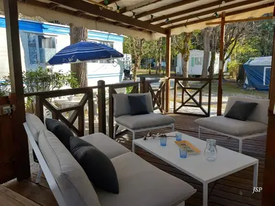 a porch with a couch and two chairs and an umbrella at Mobilhome Les volets bleus in Vaudreuille