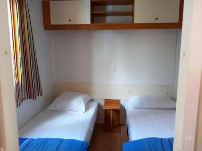 two twin beds in a room with a window at Mobilhome Les volets bleus in Vaudreuille