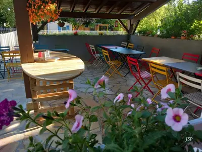 a patio with tables and chairs and pink flowers at Mobilhome Les volets bleus in Vaudreuille