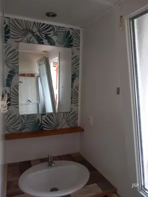 a bathroom with a sink and a mirror at Mobilhome Les volets bleus in Vaudreuille