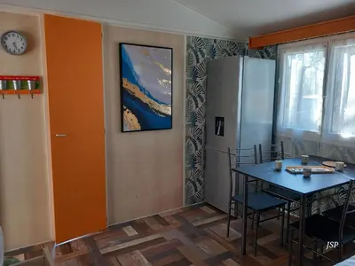 a kitchen with a table and a refrigerator at Mobilhome Les volets bleus in Vaudreuille