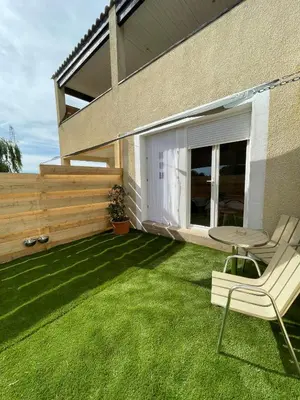 a patio with a table and a chair on the grass at Studio à l'Ecurie in Narbonne