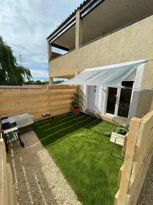 a backyard with a lawn with awning and a fence at Studio à l'Ecurie in Narbonne