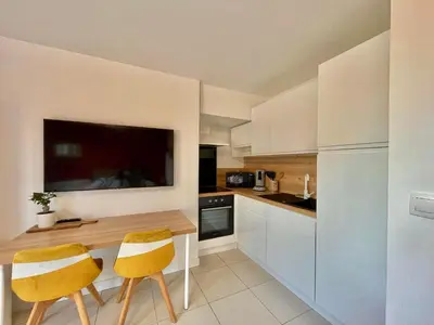 a kitchen with a wooden table and two yellow chairs at Studio à l'Ecurie in Narbonne