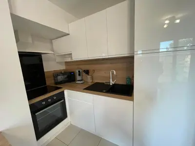a small kitchen with white cabinets and a sink at Studio à l'Ecurie in Narbonne