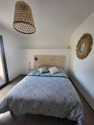 a bedroom with a bed with a blue comforter and a mirror at Chambre Le Ka-Marrant in Les Pujols