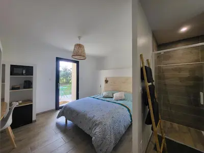 a bedroom with a bed and a desk and a window at Chambre Le Ka-Marrant in Les Pujols