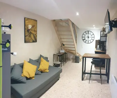 a living room with a couch with yellow pillows and a table at Le Loft in Caraman