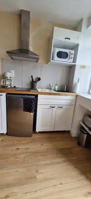 a kitchen with white cabinets and a sink and a microwave at Le Cosy in Caraman