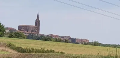 a large church in a field with a large building at Le Cosy in Caraman