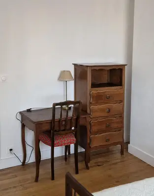 a wooden desk with a chair next to a dresser at Le Cosy in Caraman