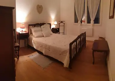 a bedroom with a bed and a table and a window at Le Cosy in Caraman