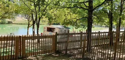 a fence with a house in the middle of a lake at Le Cosy in Caraman
