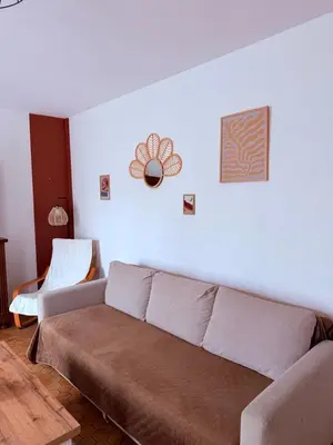 a living room with a couch and a white wall at Maison proche de la Cité avec jardin in Carcassonne