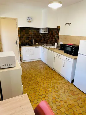 a kitchen with white cabinets and a yellow floor at Maison proche de la Cité avec jardin in Carcassonne