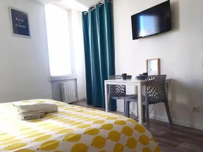 a bedroom with a bed and a desk and a television at Cosy Hypercentre Netflix in Narbonne