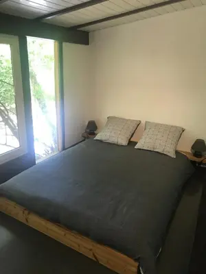 a large bed in a room with two windows at Bus atypique au bord du canal du midi et au cœur d'une forêt 2 chambres in Villepinte