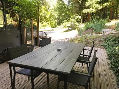 a wooden table and chairs on a wooden deck at Bus atypique au bord du canal du midi et au cœur d'une forêt 2 chambres in Villepinte