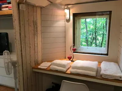 a bathroom with towels on a table with a window at Bus atypique au bord du canal du midi et au cœur d'une forêt 2 chambres in Villepinte