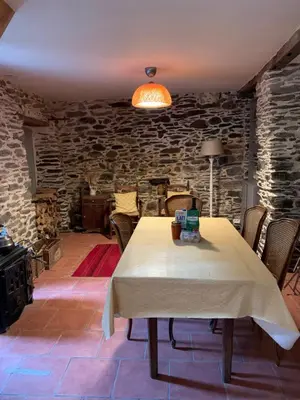a dining room with a table and a stone wall at Havre de paix in Mas-Cabardès