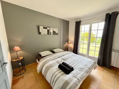 a bedroom with a large bed and a large window at Villa Louis - calme et spacieuse avec vue in Castelnaudary