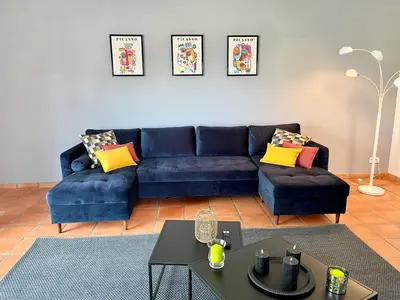 a living room with a blue couch and a table at Villa Louis - calme et spacieuse avec vue in Castelnaudary